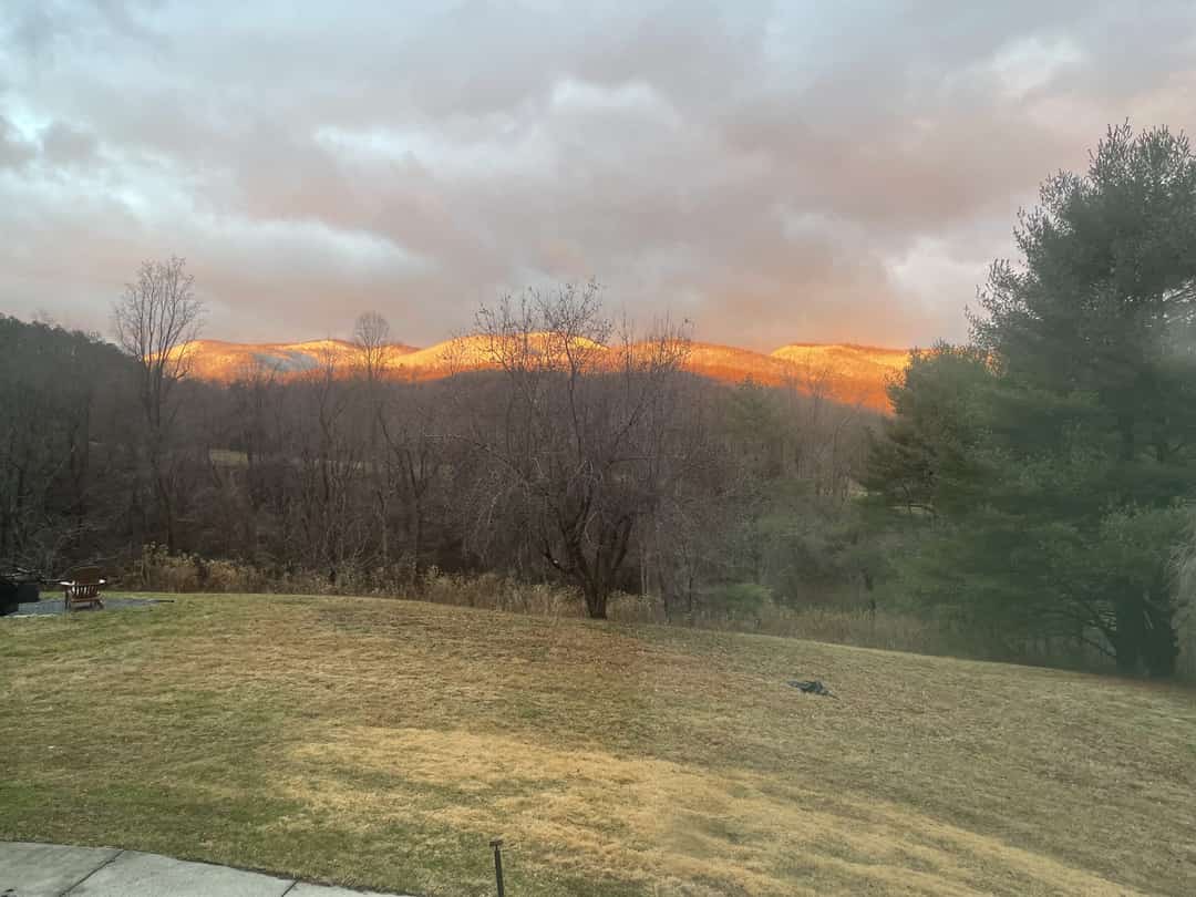 Sunrise light on a long mountain ridge above an open field.